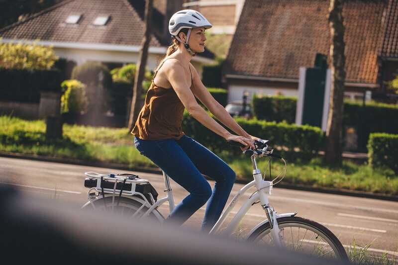 kobieta w kasku jedzie na rowerze elektrycznym