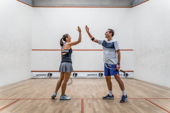 kobieta i mężczyzna w strojach do gry w squasha na korcie