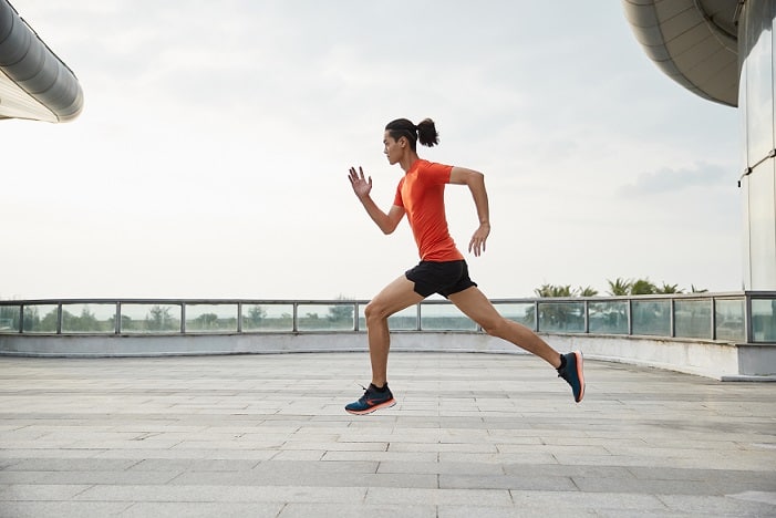 mężczyzna biegnący w krótkich sportowych spodenkach i butach do biegania