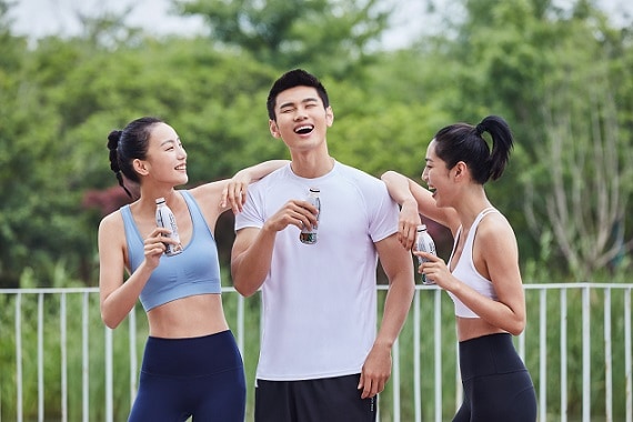 kobiety i mężczyzna w strojach sportowych z napojami w rękach